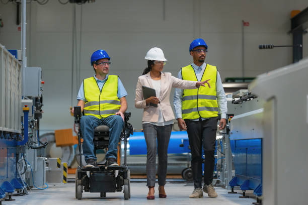 Factory manager walking alongside two workers, one of whom with a disability