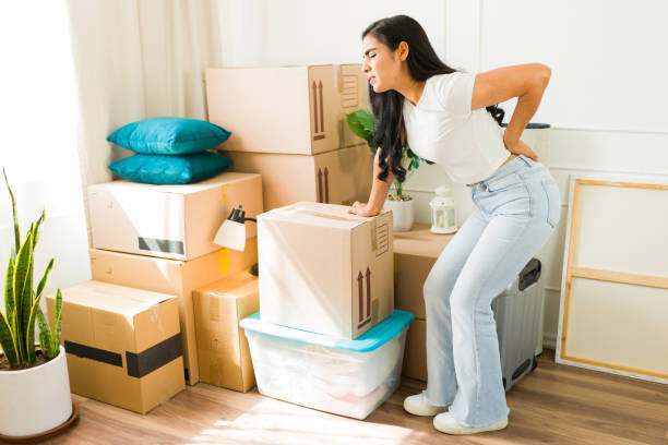 istock Latin woman suffering backache after lifting a heavy box while moving into a new apartment 2180614728