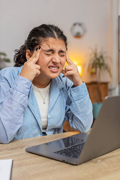 istock Tired ill Indian woman using laptop and suffering from headache problem tension sitting at table 2180616236