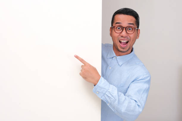 istock A man peeking behind wall showing wow face while pointing at the wall 2180622168
