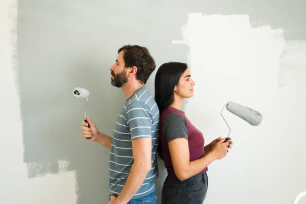 istock Good looking couple standing back-to-back with paint rollers, assessing their home renovation progress 2180627238