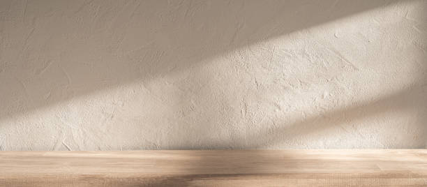 istock Soft sunlight illuminates a textured wall and wooden surface in a serene indoor setting during the afternoon 2180630043