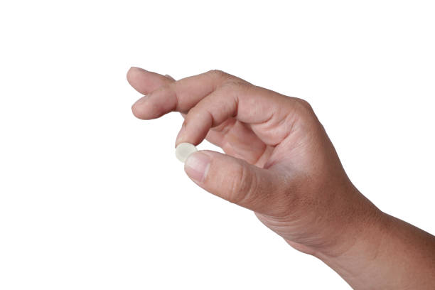 istock Hand holding one white pill between fingers, cut out isolated 2180633531
