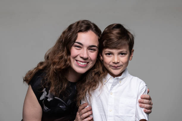 istock Smiling young woman posing with her son on gray background 2180634155