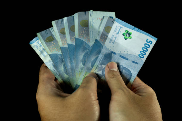 istock man's hand holding on some 50000 rupiah indonesian currency on solid black background 2180634974