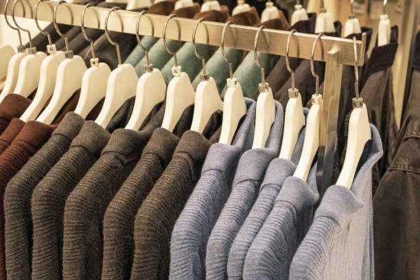 istock Warm knitted sweaters hang on white hangers in clothing store. 2180641332