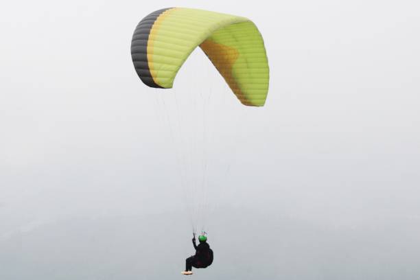 istock paragliding pilot flying in the blue sky with white clouds 2180643209