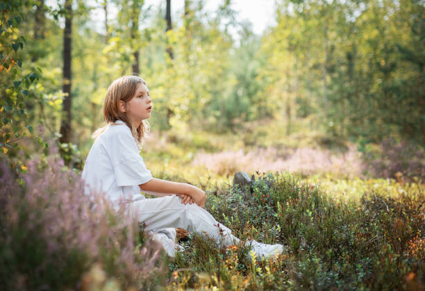 istock A young child sitting quietly in a serene forest, surrounded by vibrant greenery during a sunny afternoon 2180663206
