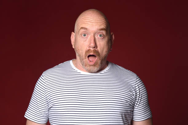istock surprised man with open mouth on red background 2180664700