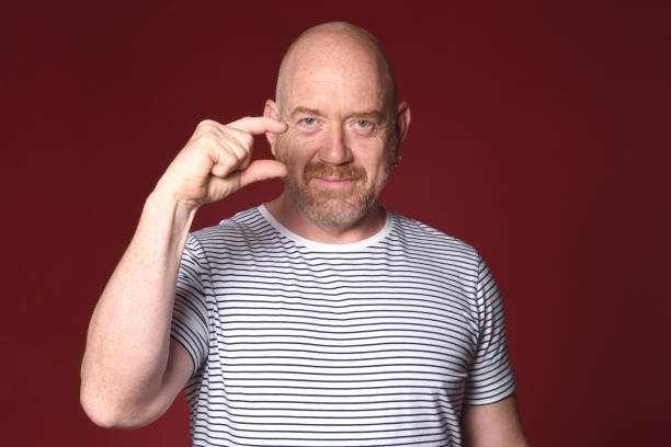 istock Man who shows with his fingers that he is small on red background 2180664721