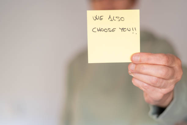 istock Person Holding Sticky Note With 'We Also Choose You! Message 2180667402