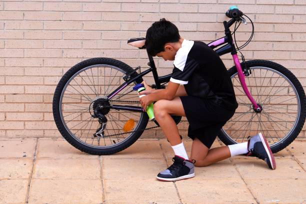 istock preteen boy on bicycle route, greasing bicycle chain 2180671428