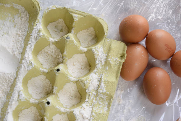 A carton of eggs is positioned right next to several brown eggs, indicating a variety of egg types available for various culinary uses
