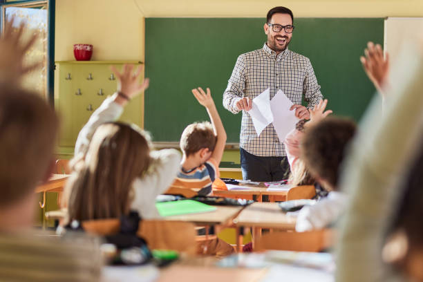 istock Happy male teacher giving a lecture at elementary school. 2180674436