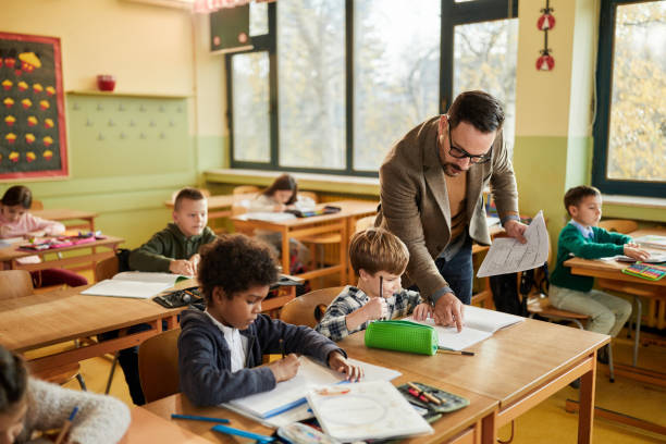 istock Young male teacher assisting his students on a class at elementary school. 2180674523