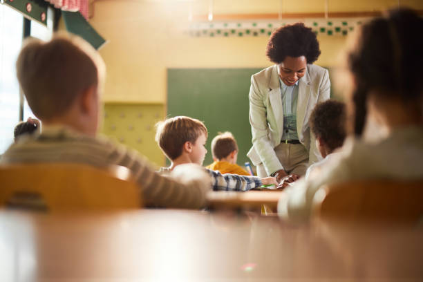 istock Happy black professor assisting schoolboy on a class at school. 2180674671
