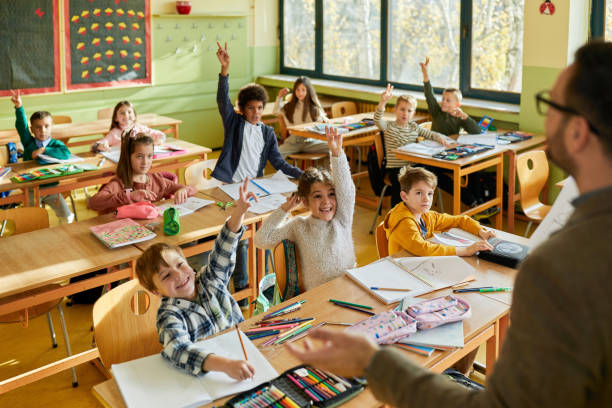 istock Happy students raising hands to answer the teacher's question on a class. 2180674854