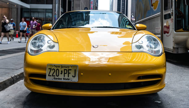 New York City, USA - July 22, 2023: 2002 Porsche 911 Carrera convertible yellow car, low front view.