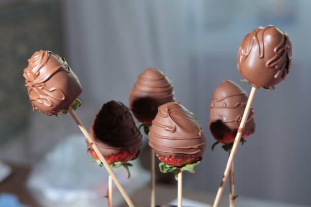 Whole chocolate covered strawberries on sticks.