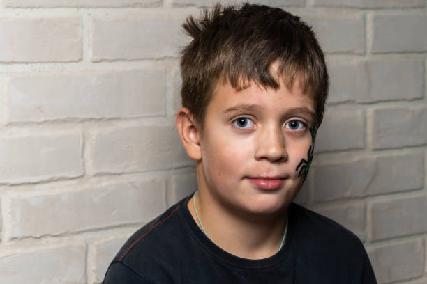 little kid boy with face painted with a spider web, Activity for kids on birthday celebration part, face painting, fun and happiness