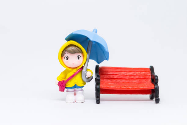 Miniature girl holding blue umbrella isolate on white background, rainy season concept, school girl in raincoat on white background