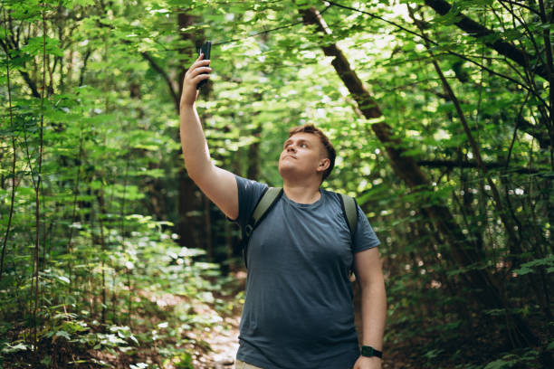 istock Sad blonde man got lost and could not find an internet connection on phone while hiking alone in the forest. Male explorer looking for connection to the internet or using gps navigator app on phone 2180688352