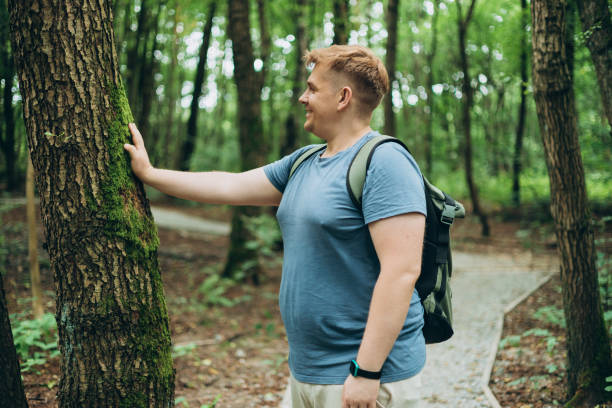istock Man with backpack Touch of tree in the forest. Caring for the environment. The ecology the concept of saving the world and love nature by human 2180688733
