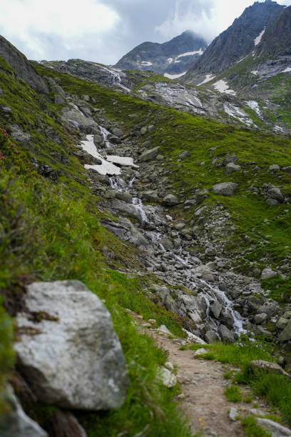 istock Mountain Path Along Rocky Stream and Green Slopes 2180689508