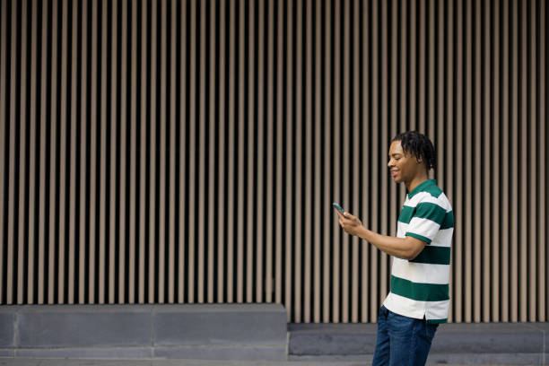 istock Happy black man using smart phone while walking on the street. 2180689573