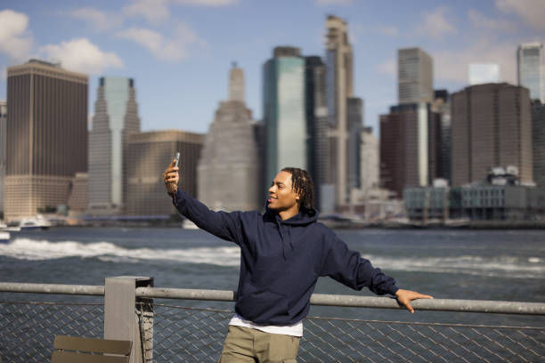 istock Happy black man taking a selfie with cell phone at riverbank. 2180689811