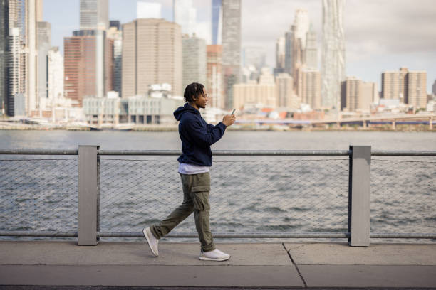 istock Happy black man using smart phone on the move by the river. 2180689988