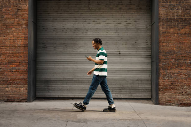 Carefree black man enjoying while using mobile phone on the move.