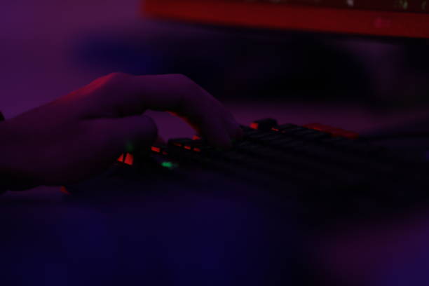 istock a person is typing on a keyboard with a purple light on the left. 2180692015