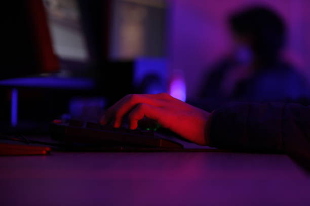 istock a person is typing on a keyboard with a purple light on the left. 2180692057