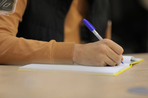 istock a person is writing on a notebook with a blue pen. 2180692100