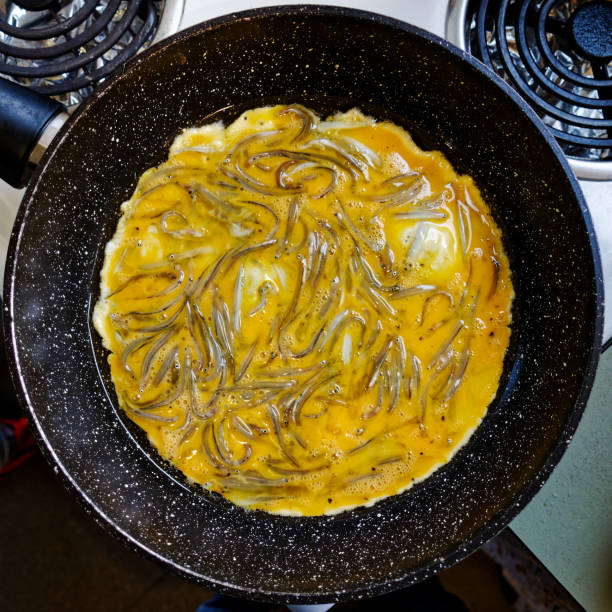 A whitebait pattie or fritter being cooked in a frying pan to make a whitebait sammy, west coast, south island, Aotearoa / New Zealand