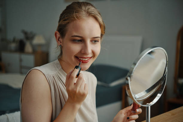 istock Young Woman Applying Makeup in Cozy Bedroom 2180694580
