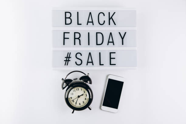 istock Creative Top view flat lay promotion composition with smartphone, alarm clock and Black friday sale text on lightbox white background copy space 2180698537