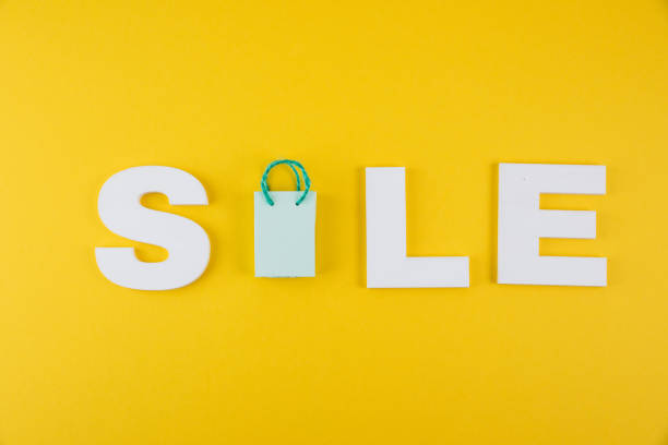 White letters spelling 'sale' on a vibrant yellow background with a tiny shopping bag representing the letter 'A'. Ideal for promotional materials and retail advertisements.