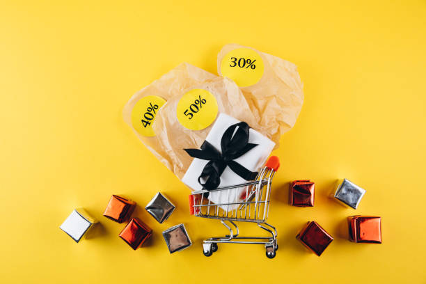 istock Shopping Cart With Discount Tags and Gift Boxes on Yellow Background 2180699013