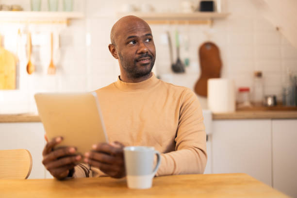 istock Latin man enjoying morning coffee and using tablet 2180701580