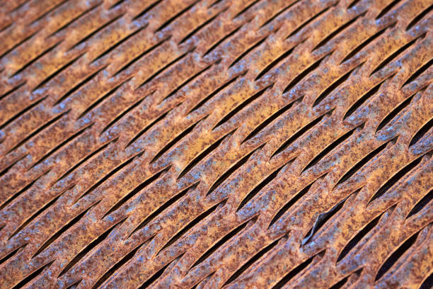 Perforated rusty metal floor sheet stamping plates texture closeup angled view. Metal stamping sheet metal manufacturing lightweight bearing flooring elements structural combine strength functionality