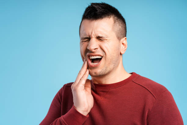 istock Middle aged man with closed eyes having teeth pain, standing on blue background 2180703187
