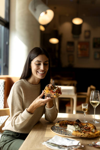 istock Beautiful young female eating pizza in a restaurant 2180704989