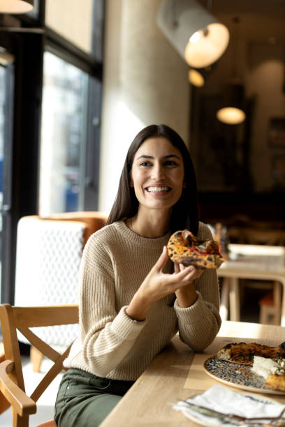 istock Beautiful young female eating pizza in a restaurant 2180705072