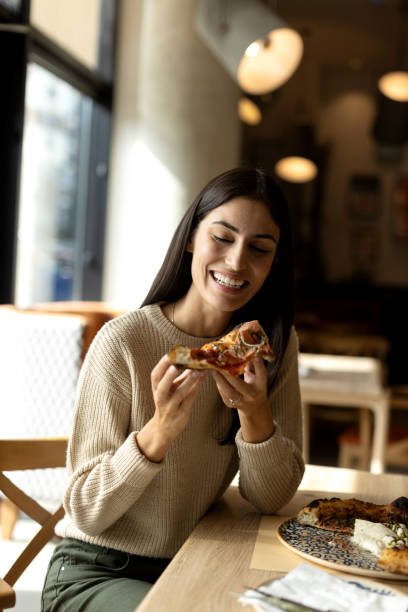 istock Beautiful young female eating pizza in a restaurant 2180705087