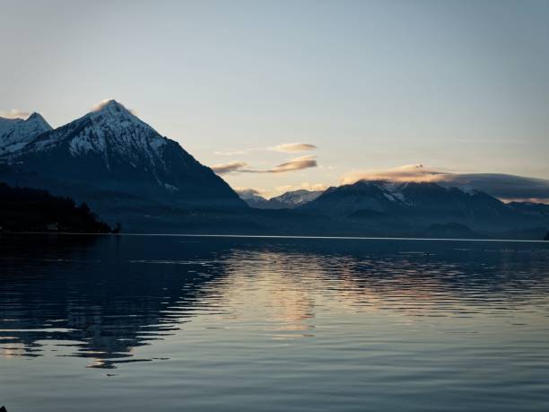 istock Snow-capped mountains reflecting on a tranquil lake at sunset. 2180707121