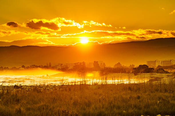 Burning sunset over sea, coastal landscape with urban building. Mediterranean coast of Spain.