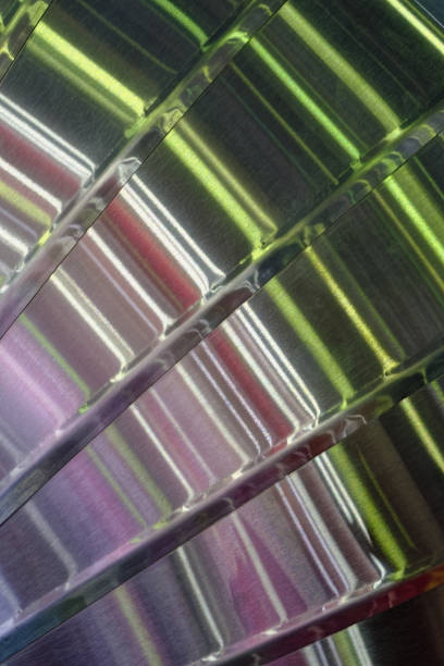 Multi-coloured light reflections on a curved surface made of brushed stainless steel, abstract industrial background