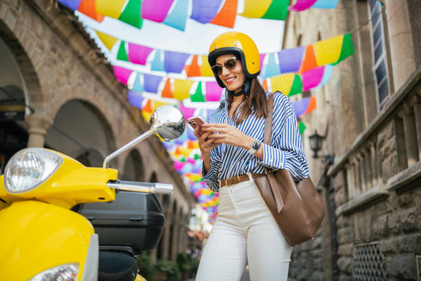 istock Woman waiting by yellow moped and using her phone. 2180714074